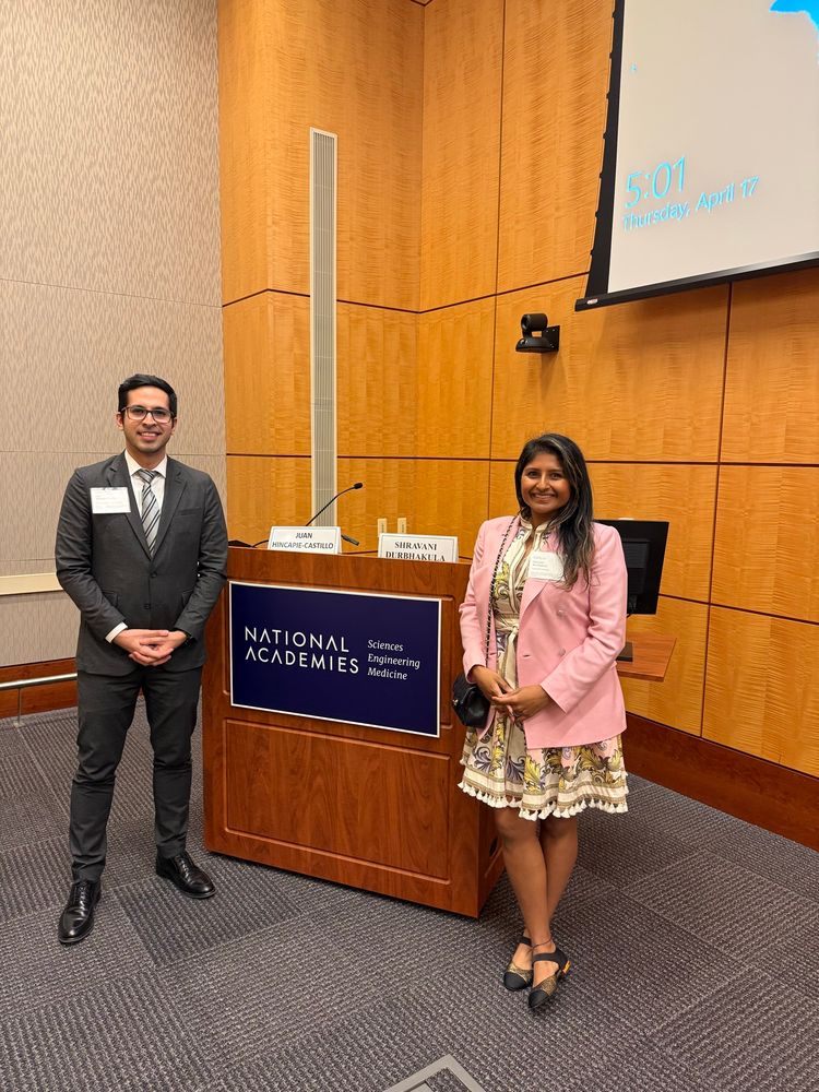 Picture of woman and man in professional attire standing up in front of a podium