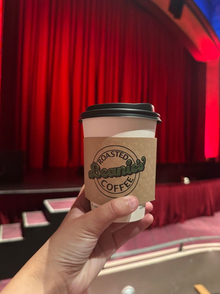 A Beanie’s coffe cup held up in front of the stage