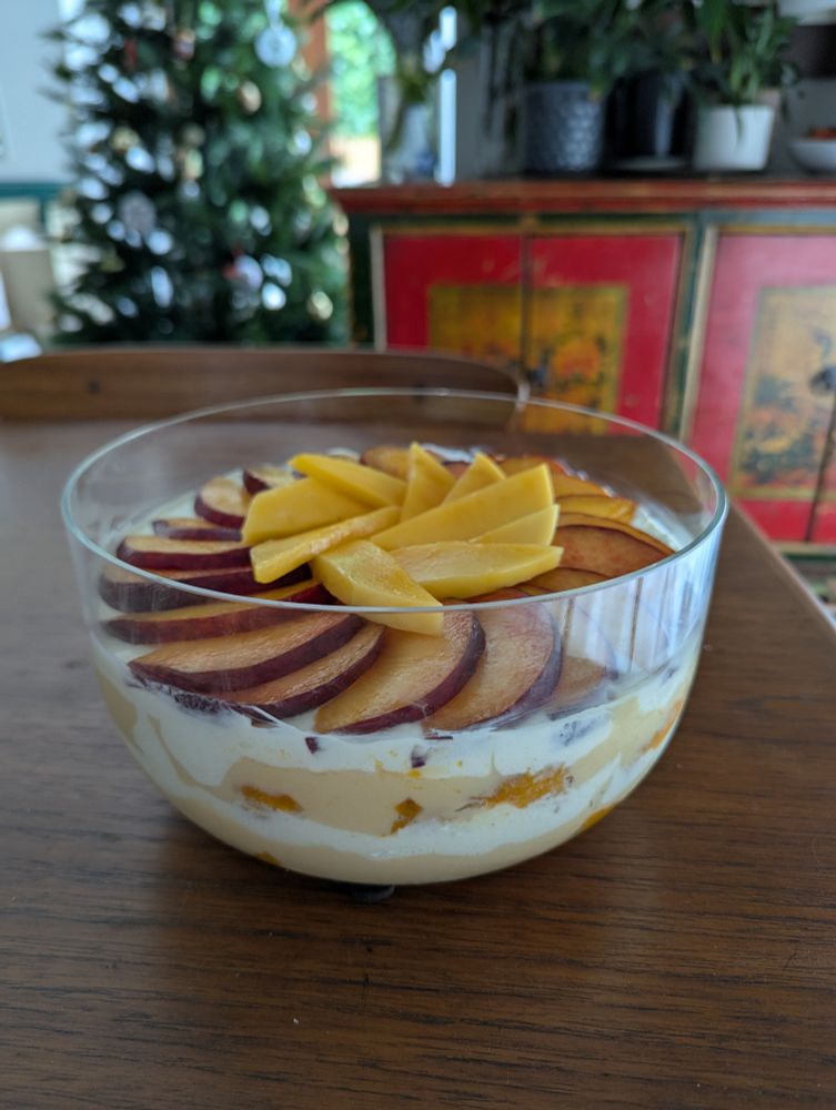 Summer fruits trifle, with Greek yoghurt, homemade custard, roasted apricots. The trifle is topped with peaches and mangos.
