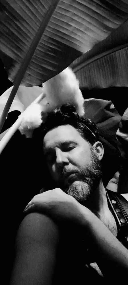 Man in leather harness and bunny ears surrounded by nature