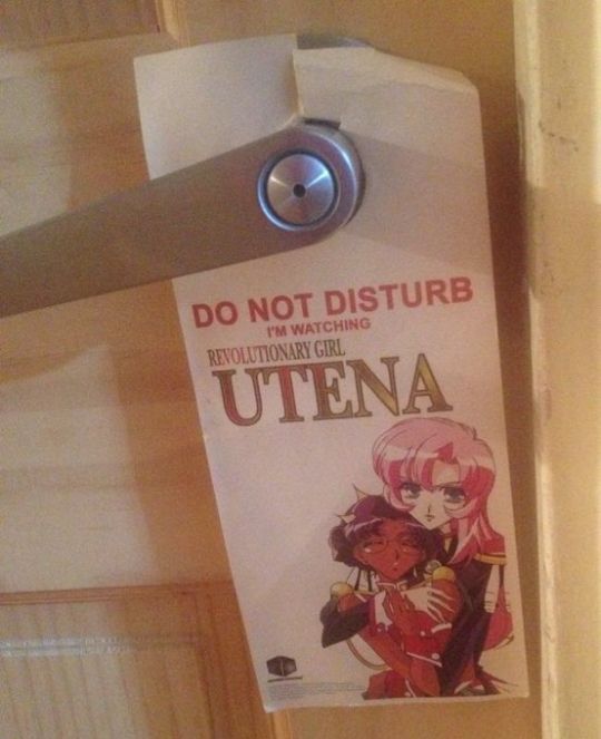 A door hanger that says "Do Not Disturb I'm Watching Revolutionary Girl Utena" and has an image of Utena holding Anthy