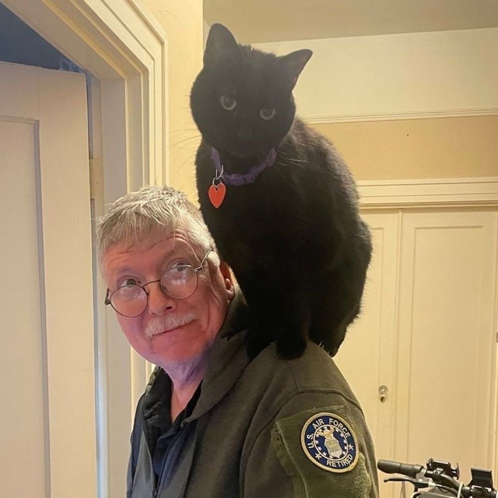 Black cat named Pywackett sitting on shoulder of an old man.