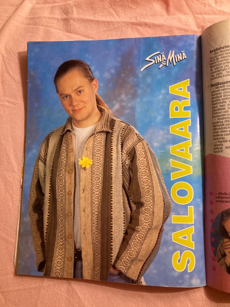 SinäMinän pikku juliste Pertti Salovaarasta. Ajanmukainen paita päällä ja keltainen kukka rintapielessä