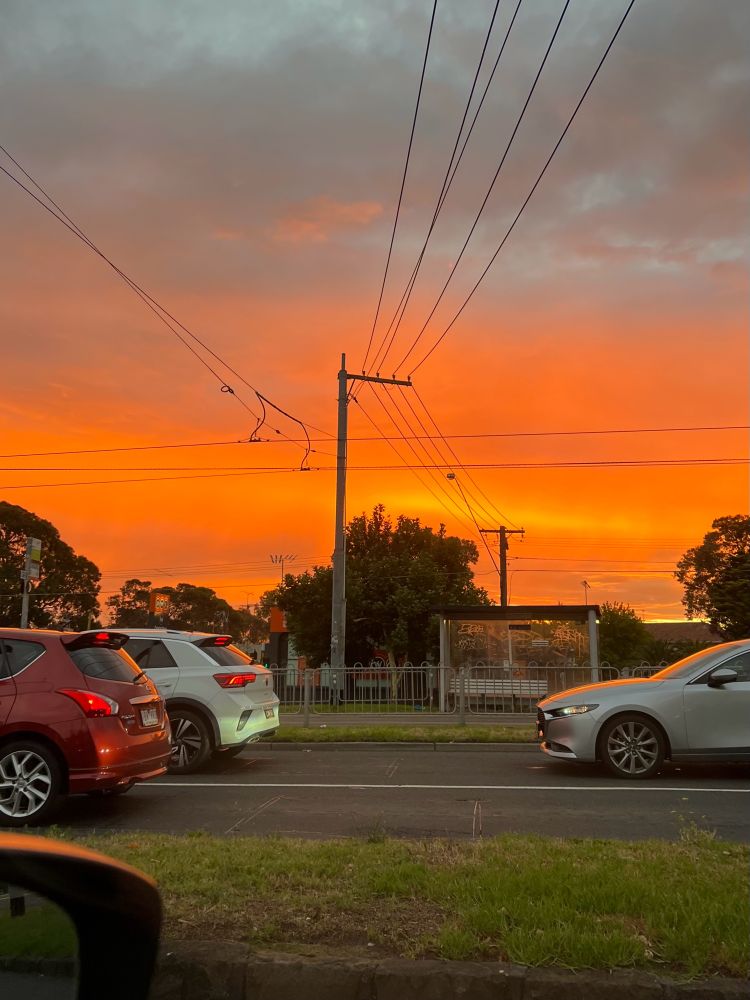 A vivid orange sunset above cars stuck in traffic. 