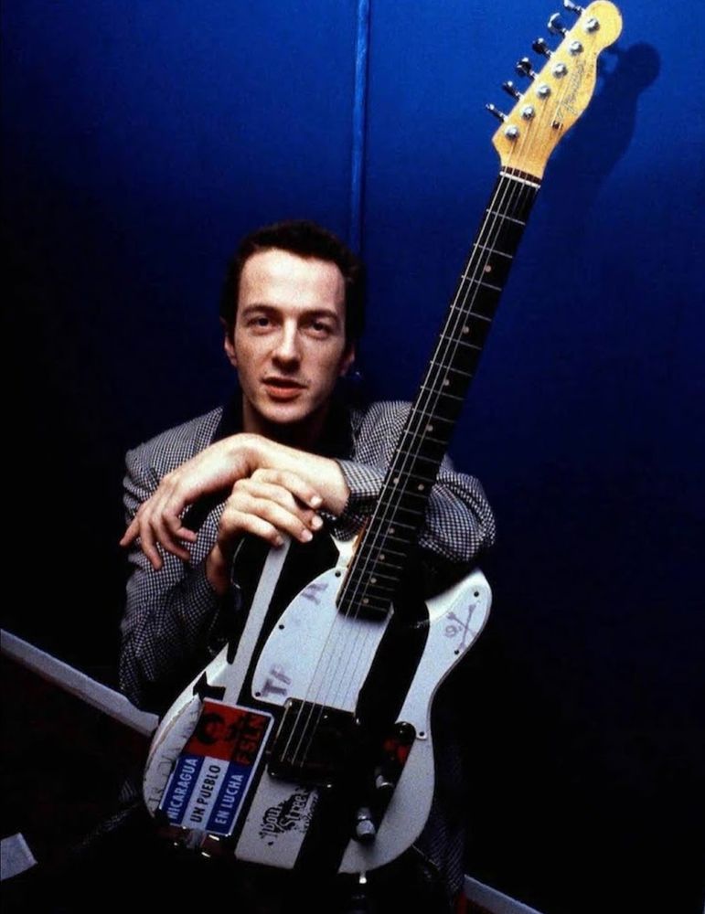 Joe Strummer of The Clash holding a guitar 