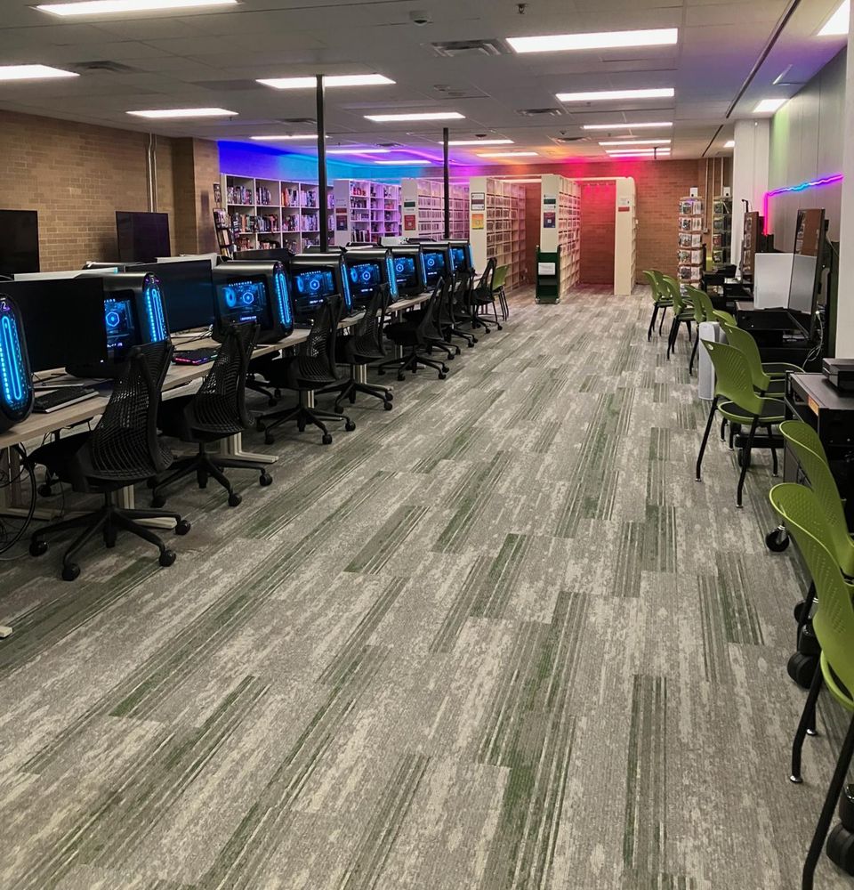 Media Library gaming space with gaming PCs in a row, console stations, and some library stacks with games.