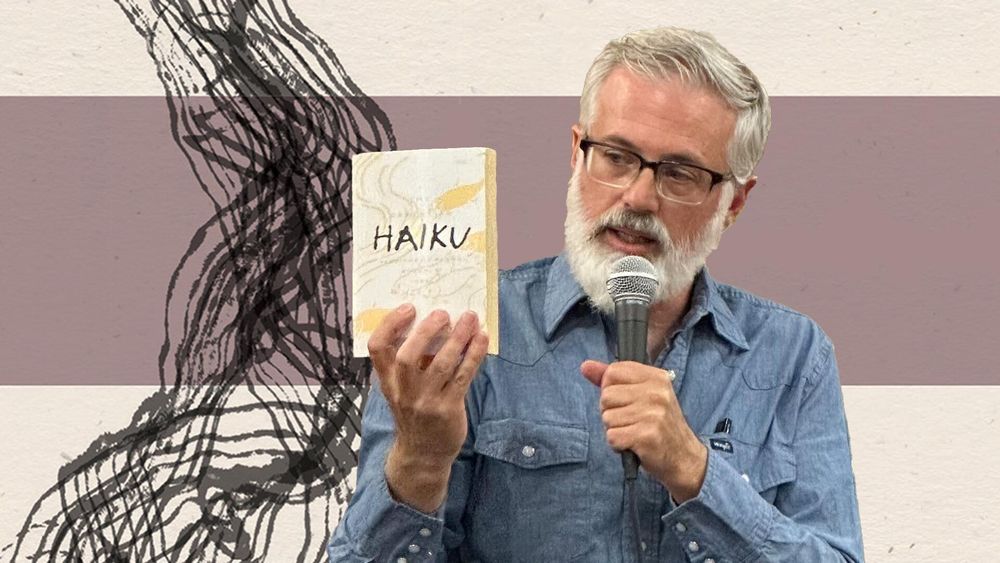 A man with glasses and a white beard (Philip Connors) holds a microphone in one hand and a copy of "Haiku" in the other, with the cover facing toward the audience.