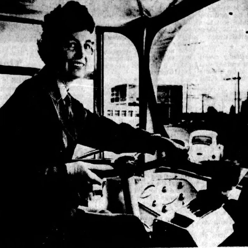 A woman driving a transit bus