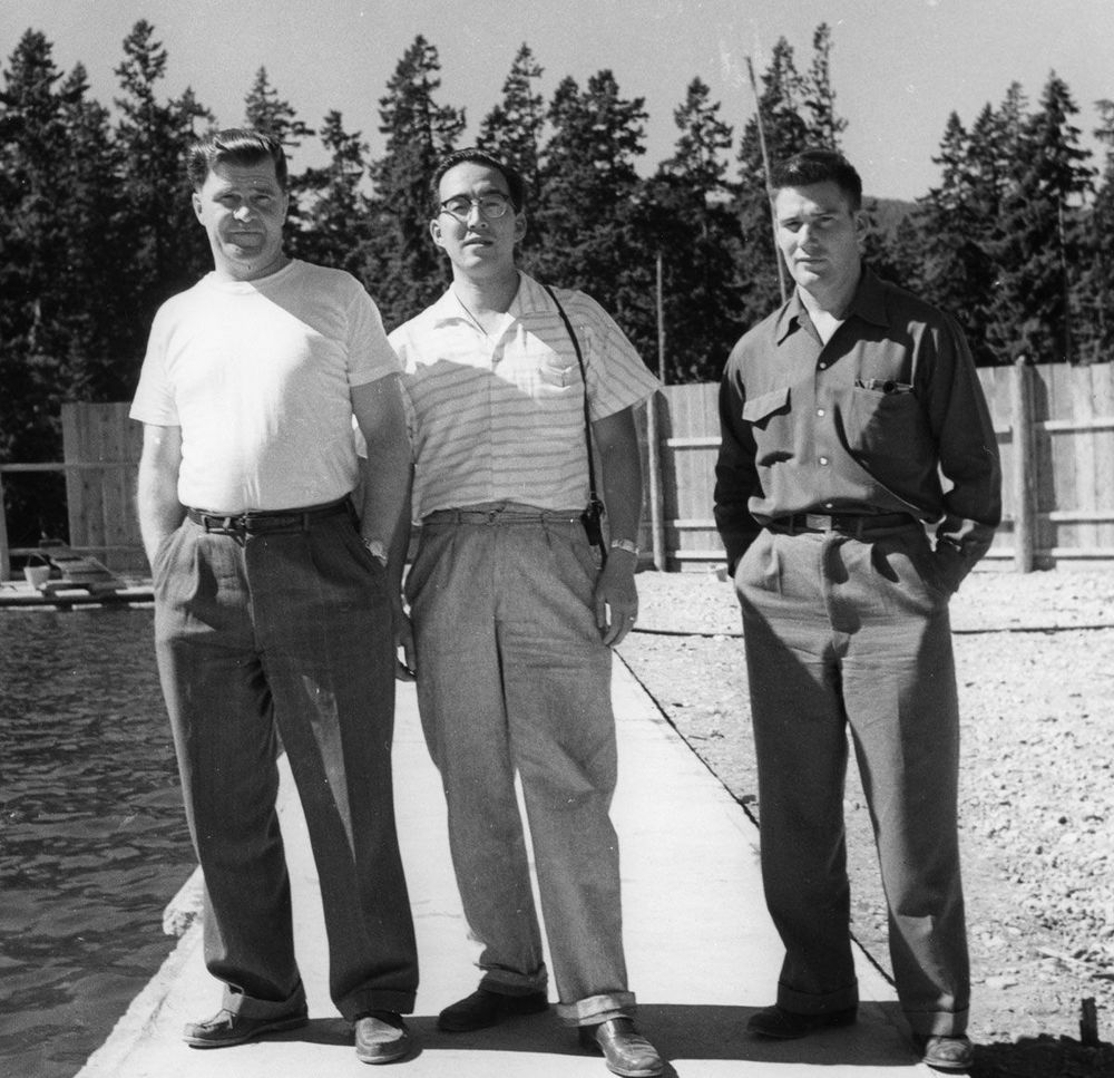 Three men standing. Man in middle is Roy Miyazawa