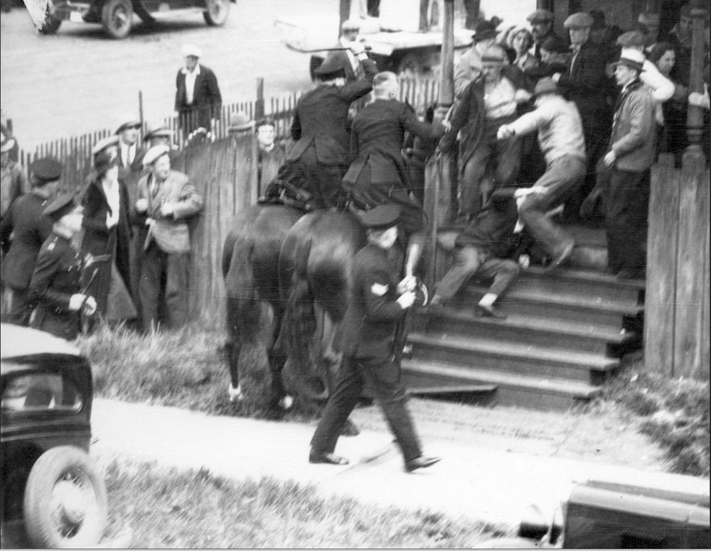 Horses and police with batons chasing men up staircase.