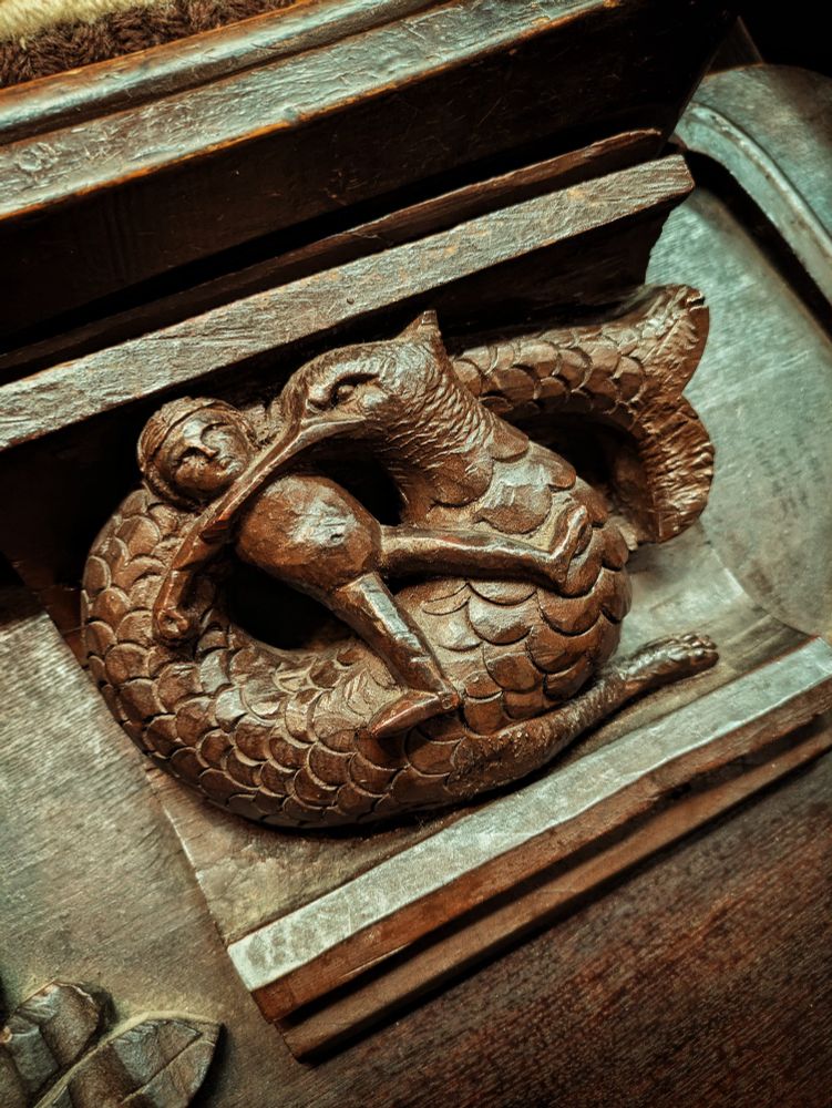 Carving of a child being eaten by a large bird-headed creature with a fish tail.
