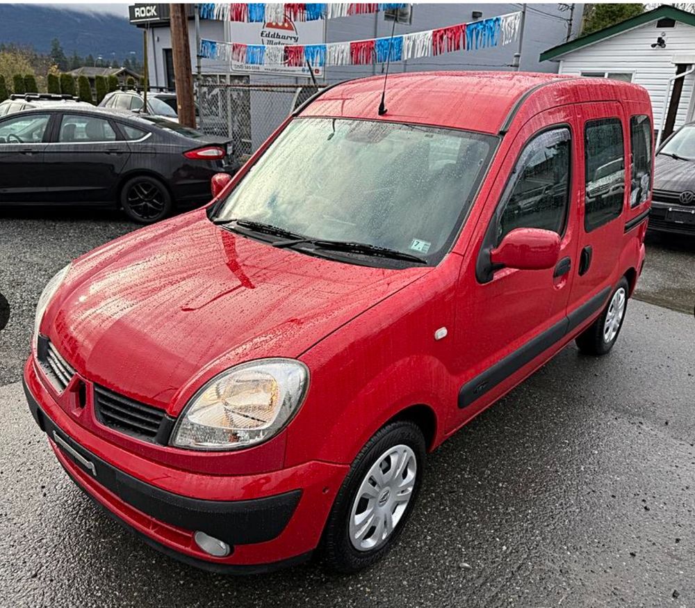 a squat, slightly silly looking tiny red van, a renault kangoo