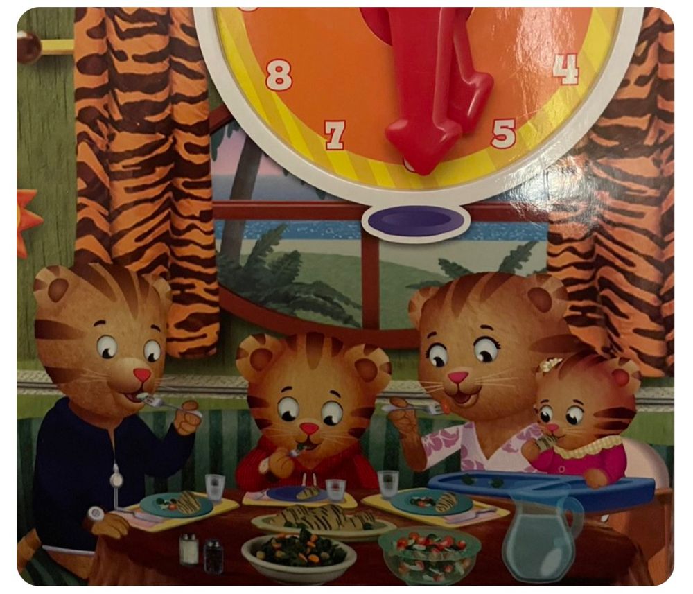 A family of tigers at the dinner table eating with a window with tiger stripe drapes behind them