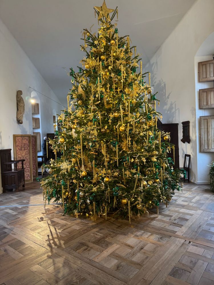 Decorated Christmas tree at one end of a long castle gallery