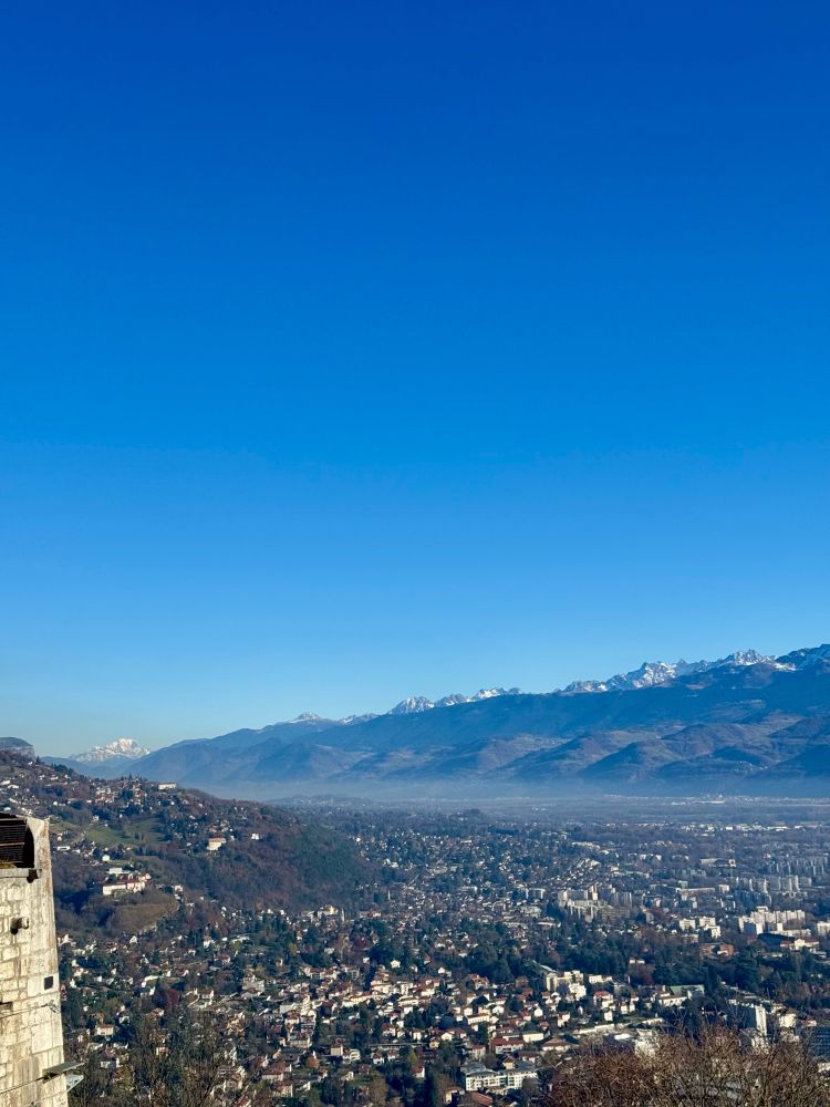 View from the top of the Grenoble Bastille looking towards Mont Blanc (the highest mountain in the Alps). The city of Grenoble stretches out into the distant mist, from which mountains rise in the background. 