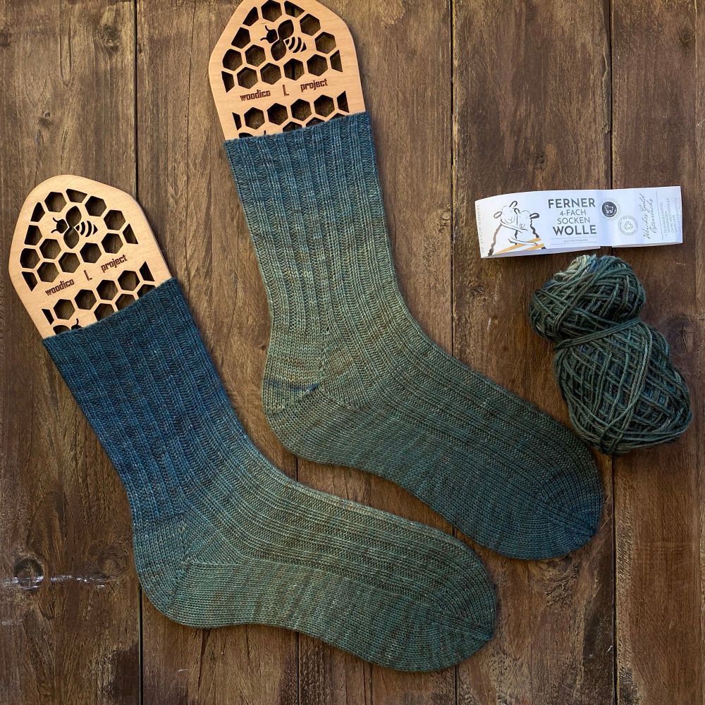 A pair of socks knitted in a simple rib pattern: k2, p2 and a short row heel with a gusset. The yarn is a self-fading yarn (fading from blue to green) 