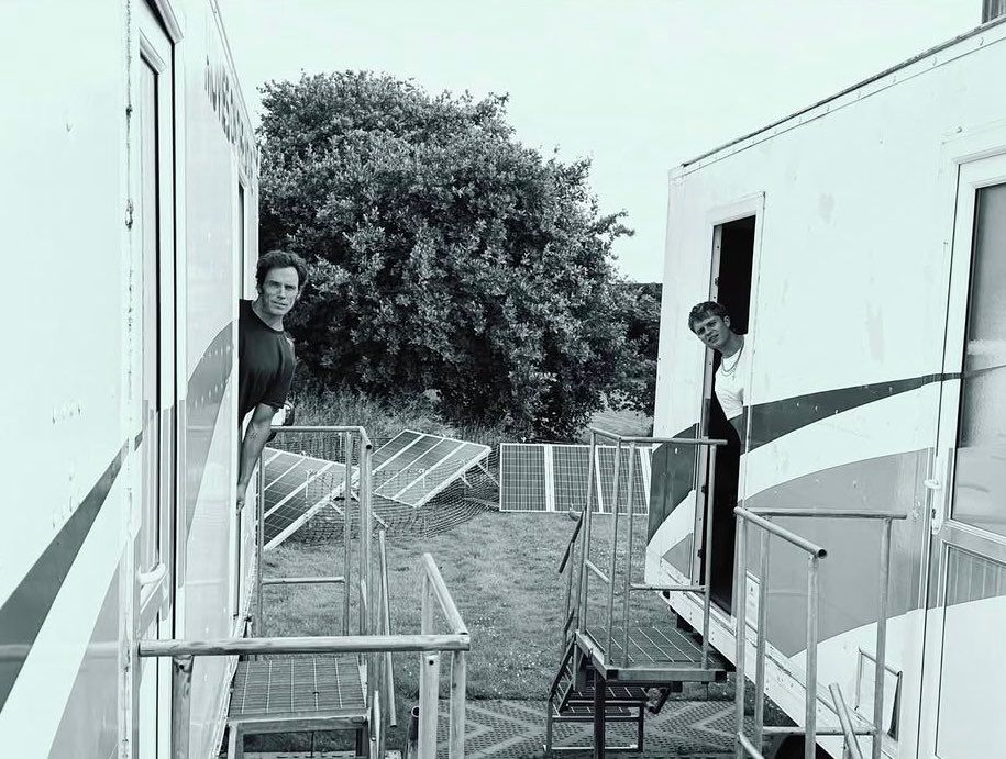 A black and white photo of Tom and Sam. They are showing up their faces from the van.
