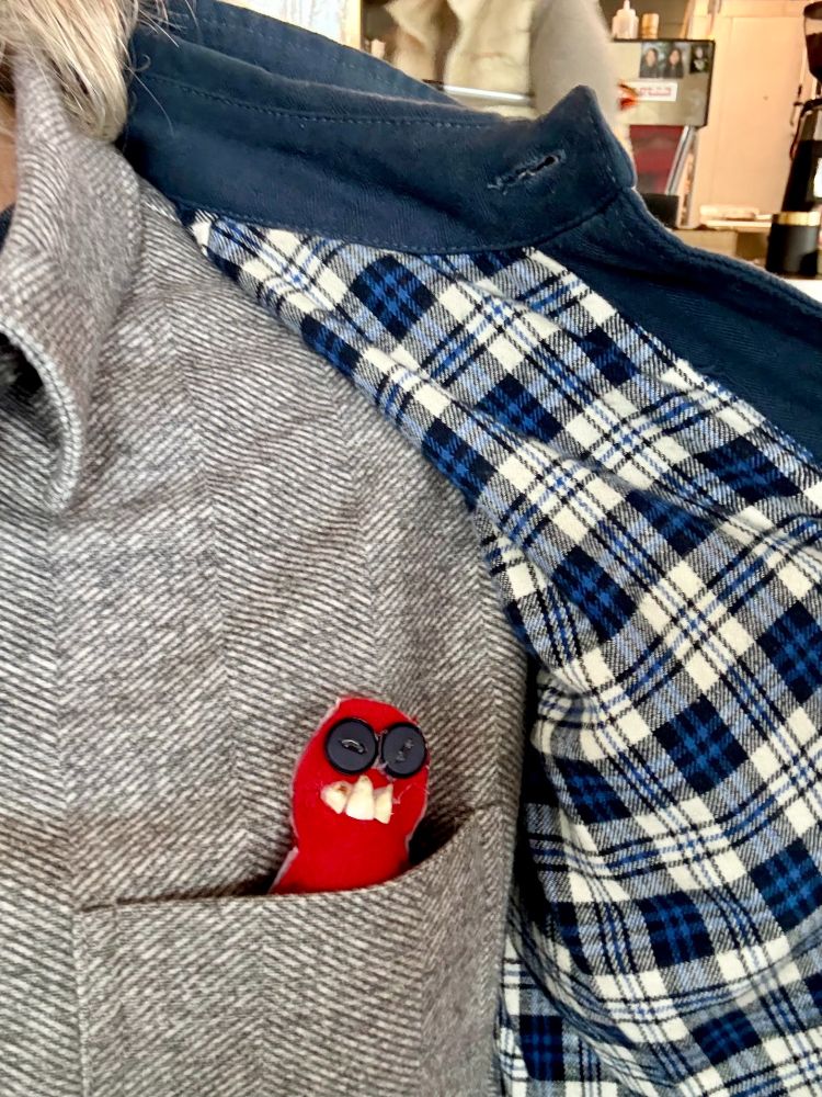 Creepy doll with teeth in breast pocket of shirt, covered by jacket.