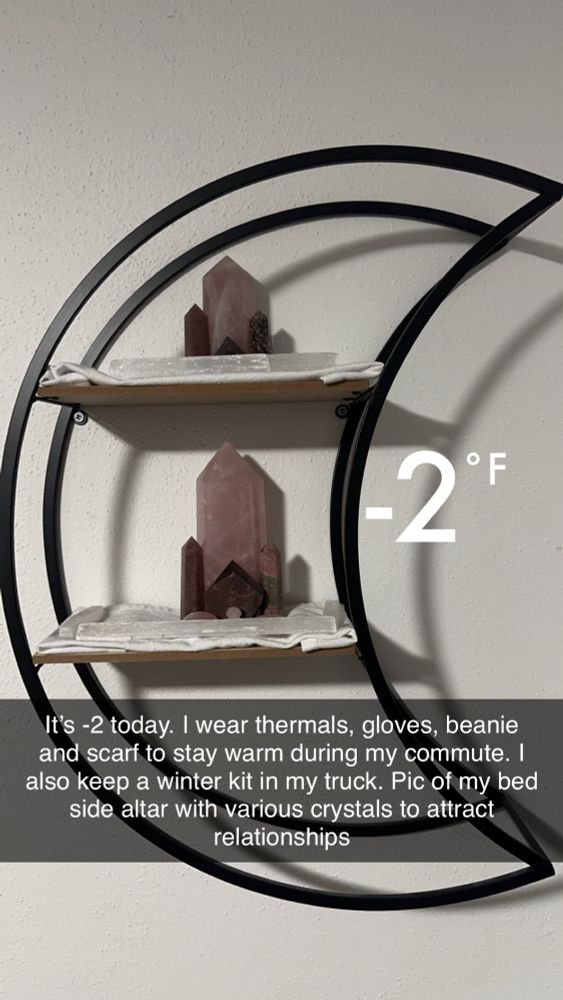 Pic of a moon shaped, hanging shelf. There are two shelves with various pink and red crystals. 