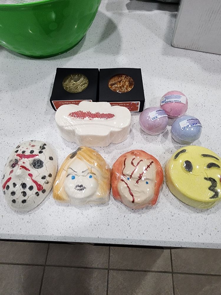 Bath products - 2 loofah soaps, a maxi packed bathbomb shaped like a menstrual product but scented Tuscany and herb. 3 golf ball sized bath bombs in rose, lilac, and blue sage, 3 Halloween bath bombs - Jason, Tiffany Valentine, and Chucky. Finally a yellow kissy face emoji which smells of orchid 