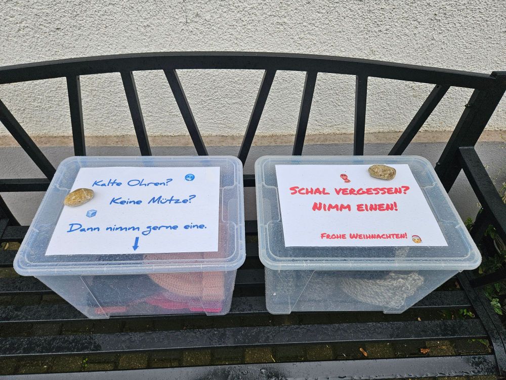 A bench in front of a house,  on top two transparent boxes with hats & scarfs in; photos of the boxes with signs on top, asking people to help themselves if they're cold.