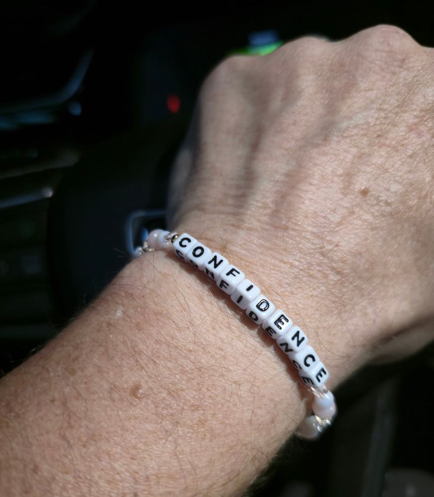 It's a friendship bracelet with the word Confidence and pink beads.