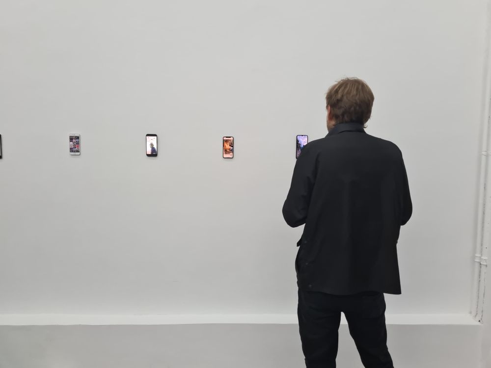 James Bridle's work Dronestagram on display on a mobile phone pinned to the wall in an exhibition.
