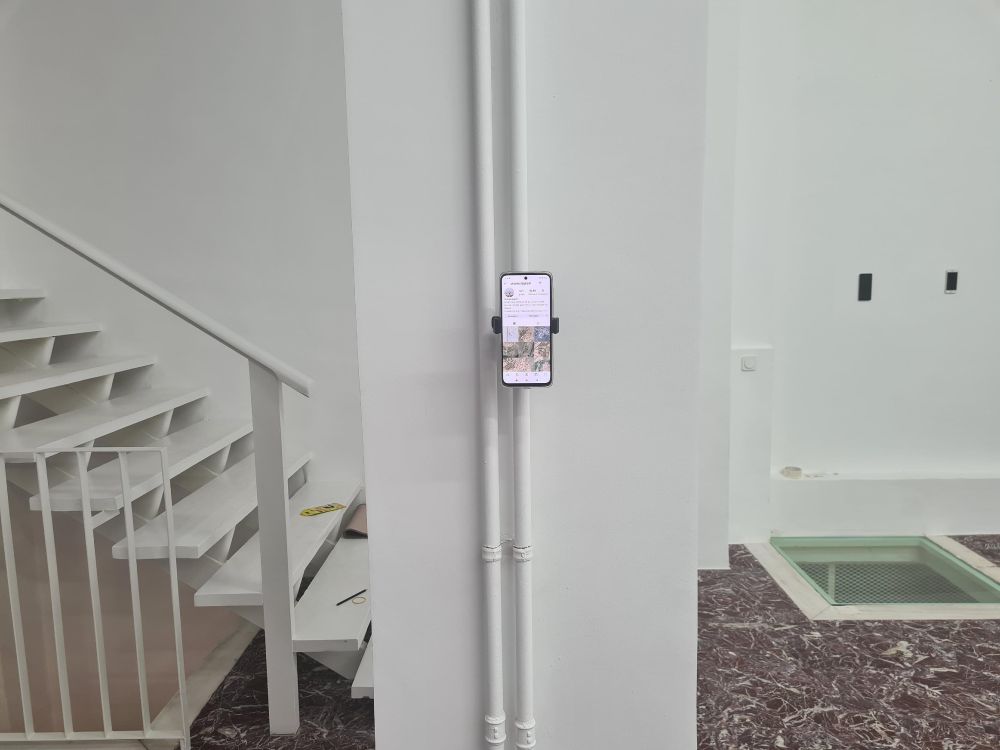 James Bridle's work Dronestagram on display on a mobile phone pinned to the wall in an exhibition.