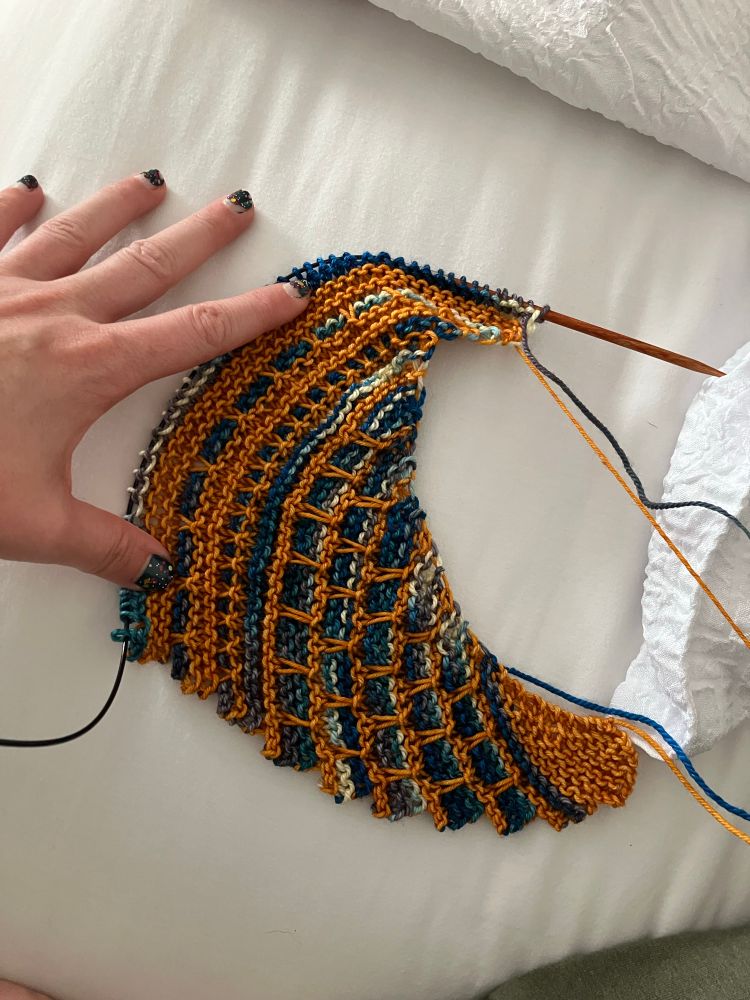 Most recent WIP: Dutch Tulips shawl featuring malabrigo in sunset and Theodora’s Pearls in Palladio: Durango. A mosaic pattern crescent shaped shawl with a golden yellow main color and a variegated teal as the accent. 