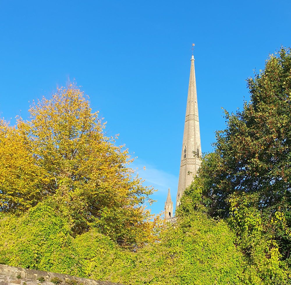 Blue skies Iver a church steeple and trees