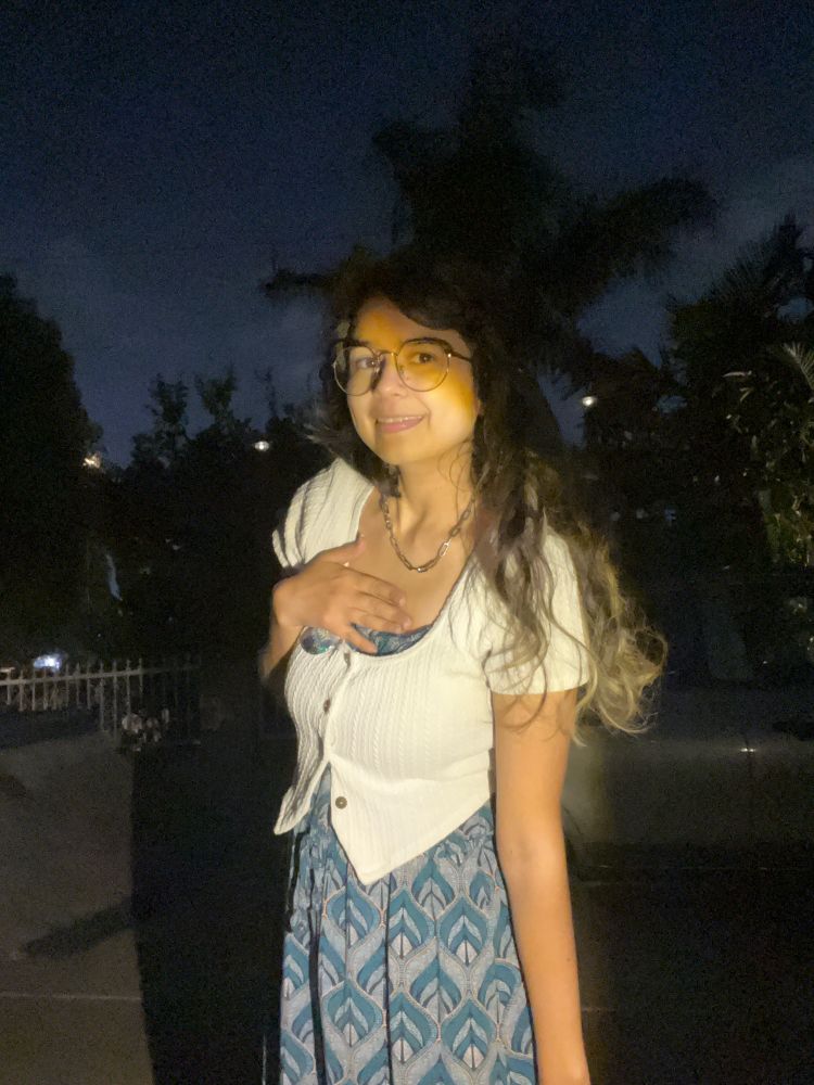 Myself with a spotlight on wearing white top and a blue feather printed dress