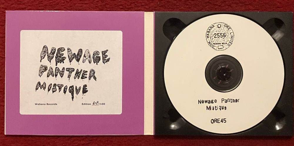 Inside cover of CD digipak on left: white sticker with NEWAGE PANTHER MISTIQUE
Wabana Records 68/100 in black 
White CDr on right with black  DOM WABANA ORE LIMITED 2556 circular stamp at the top.
Newage Panther Mistique ORE45 in black type below. 