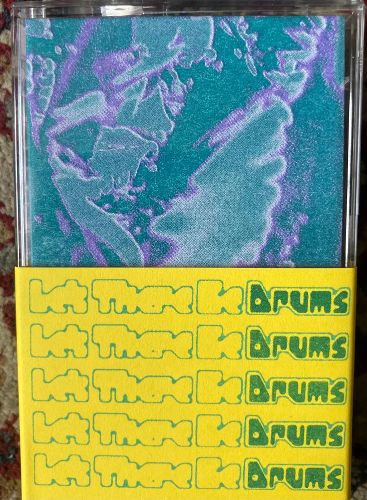 Blue/green/purple cassette cover with a thick yellow band on the bottom half with the words ‘Let There Be Drums’ in Green/blue text. 