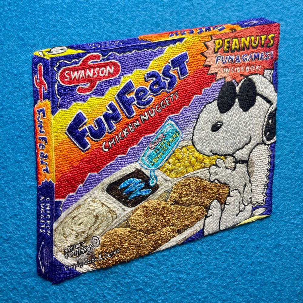Embroidery of an early 90s Fun Feast frozen meal with cool Snoopy gesturing towards a meal of breaded chicken nuggets, mashed potato, corn, and a brownie being drizzled with disturbingly blue icing from a floating icing pack. 