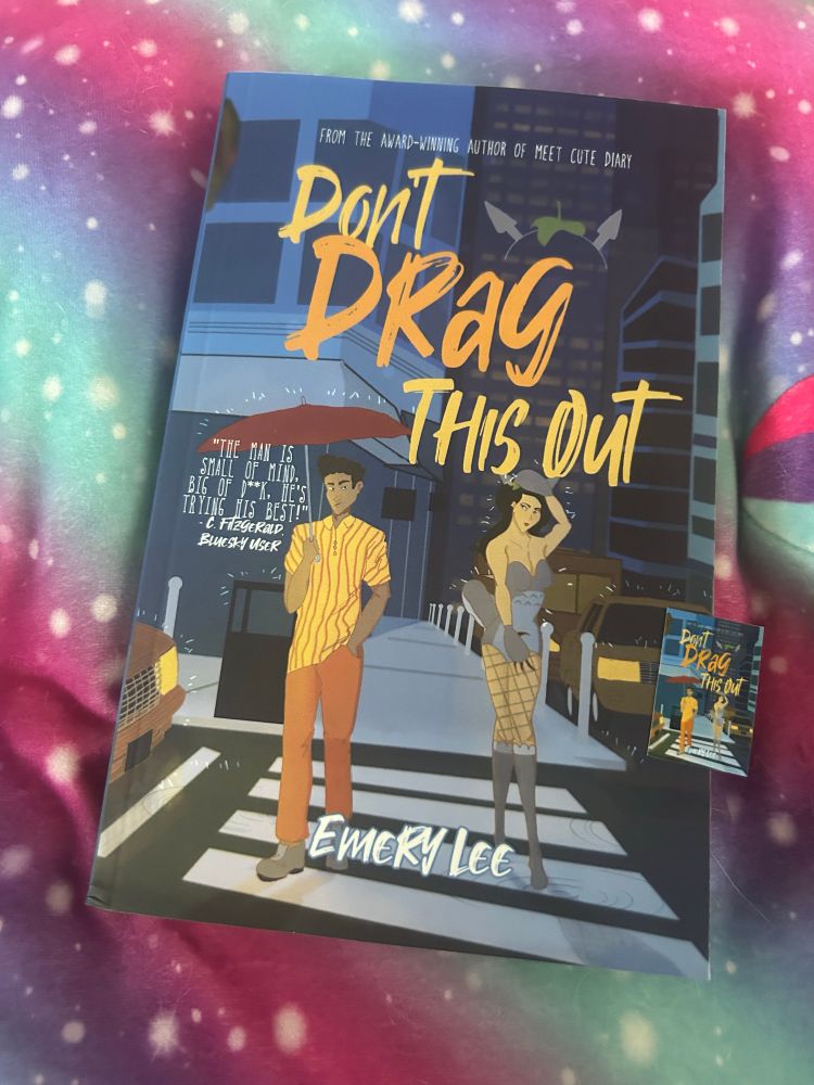 The book, “Don’t Drag This Out” by Emery Lee, resting on multicolored fabric 