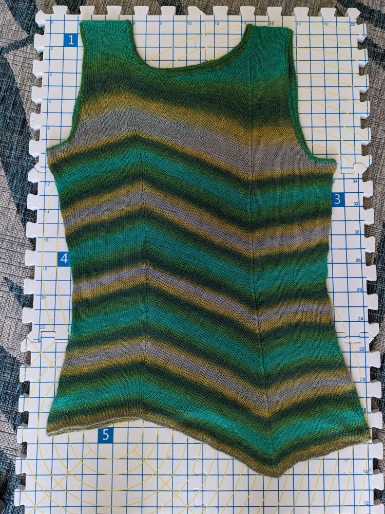 Striped asymmetrical knitted tank with bias panel on blocking boards.

