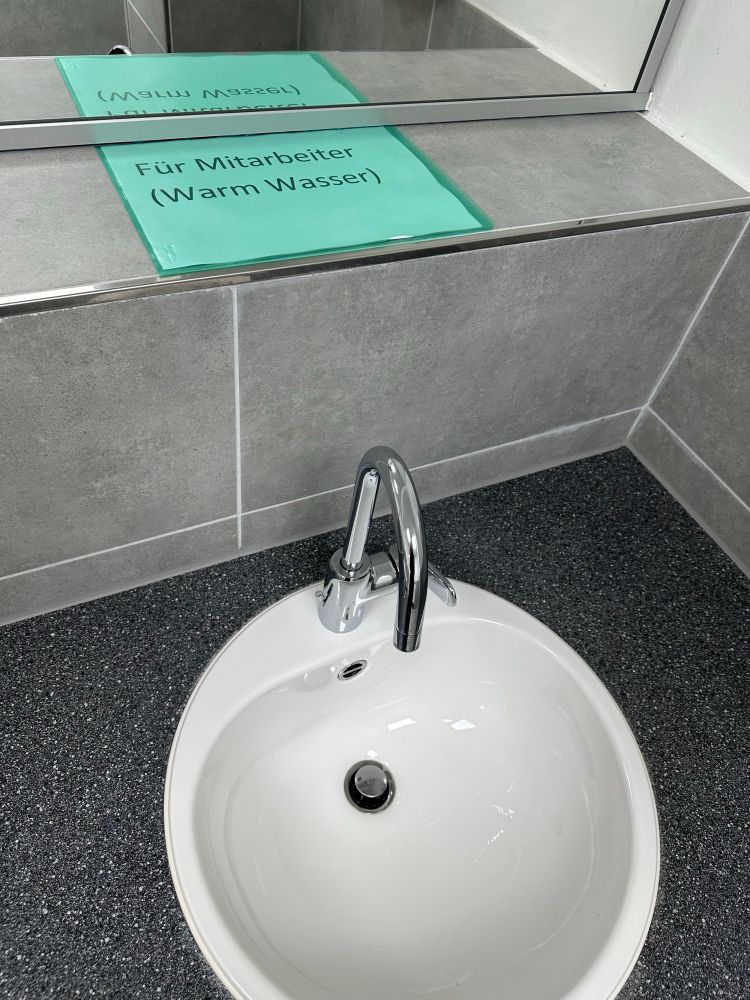 Waschbecken mit Schild „Für Mitarbeiter (Warmwasser)“