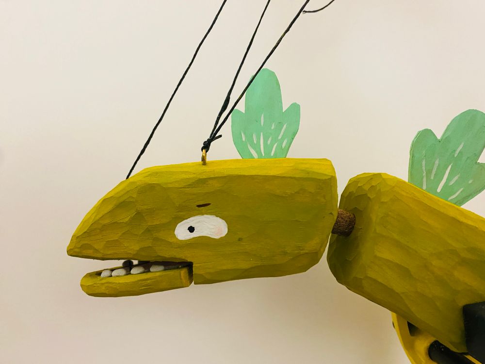 the head of a green godzilla-esque monster puppet