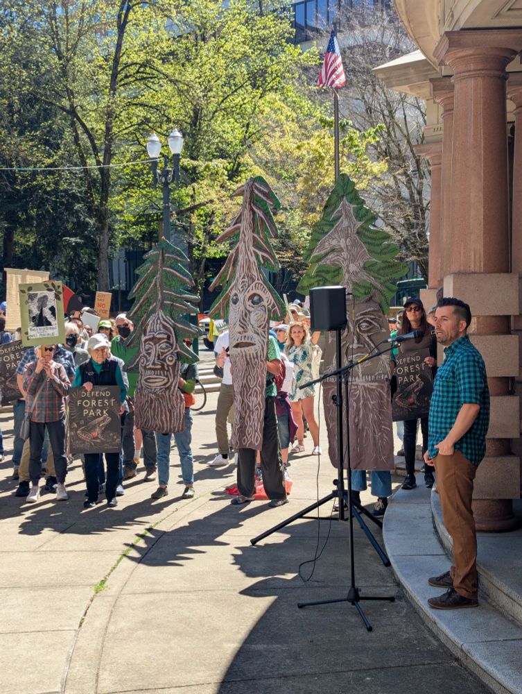 Micah Meskel of the Bird Alliance of Oregon (fka Portland Audubon) speaks to rally attendees holding tree artwork