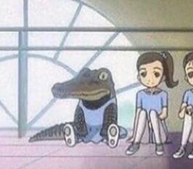 A little crocodile in a ballet outfit sitting on the floor in front of a window in a light blue/purple ballet costume. On its right are two girls with dark hair in the same blue/purple ballet outfits. 