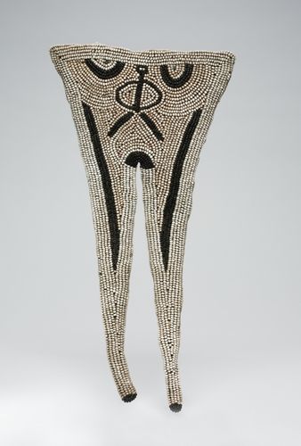 This is an exquisite example of a rare type of swallowtail-shaped apron worn by young female initiates until the mid-19th century. On the upper portion, the black beads were applied in such a way that they can be read as a human face or even as a full figure. In fact, the overall form of the apron can be viewed as representing the lower torso and legs of a woman with a neatly marked pubic region.