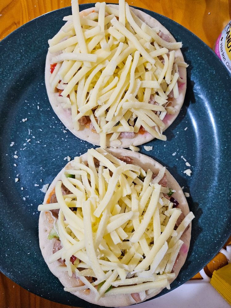 Grated cheese on top of the pizzas