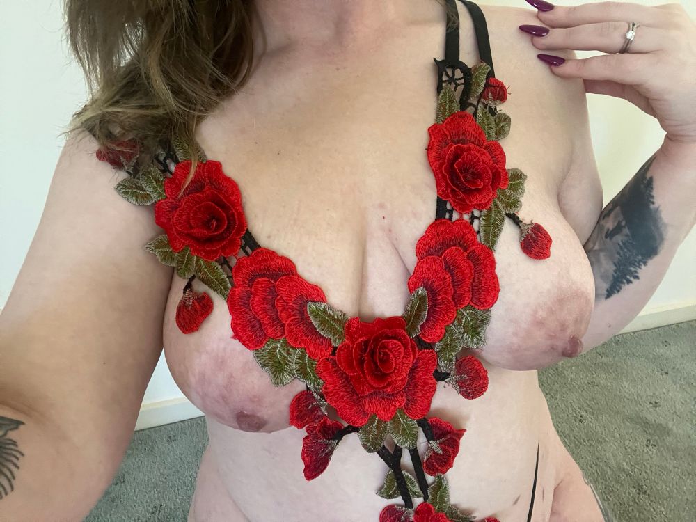 Kayla is wearing a delicate rose lingerie piece that exposes her breasts and her tummy. She is seated as she is taking her selfie. As always, her hands are in an awkward position 