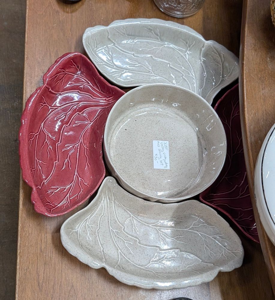 Red and cream serving dishes. The center dish is round and surrounded by dishes shaded similar to lungs and with what appear to be branching veins across their surfaces. 