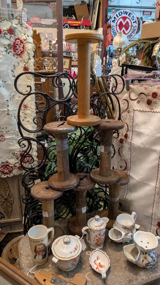 Wood spools shaped like dumbbells stacked on top of each other. There are some small dishes below. 