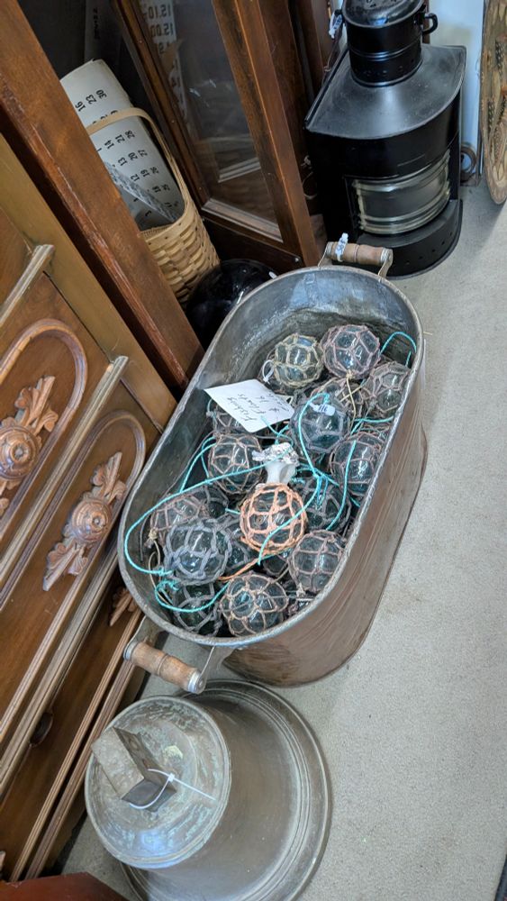 Glass balls wrapped with rope inside of a large metal tub. Each ball is about 5 inches wide. 