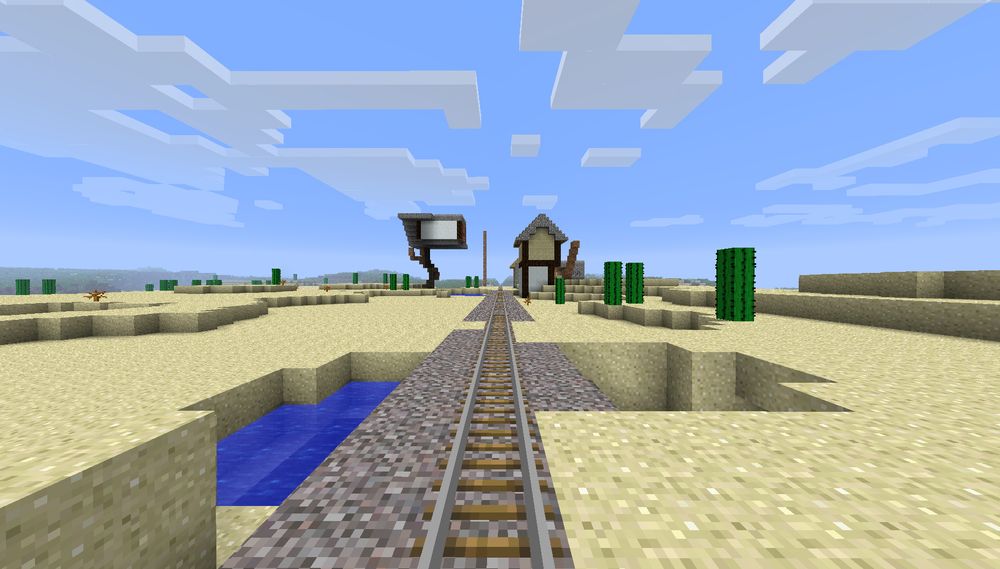 A screenshot from the game minecraft, the player is standing in a desert, looking down a minecart track, in the distance there is the outlines of a couple of tudor style timber framed buildings covered in a lot of dirt scaffolding