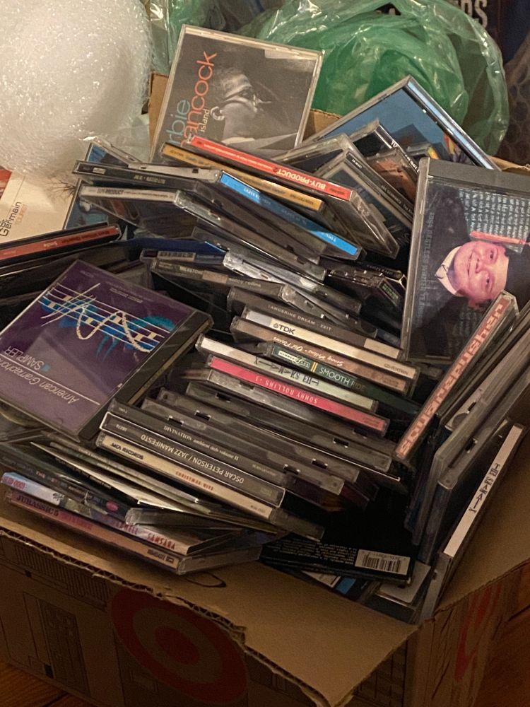 A messy, chaotic packing box full of CD's from the 90's and early 2000's
