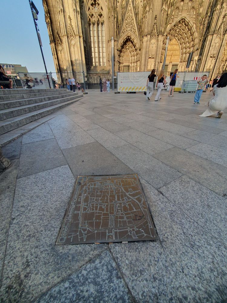 Plan des römischen Köln als Bronzeplatte im Boden. Dahinter in einigen Metern der Dom.