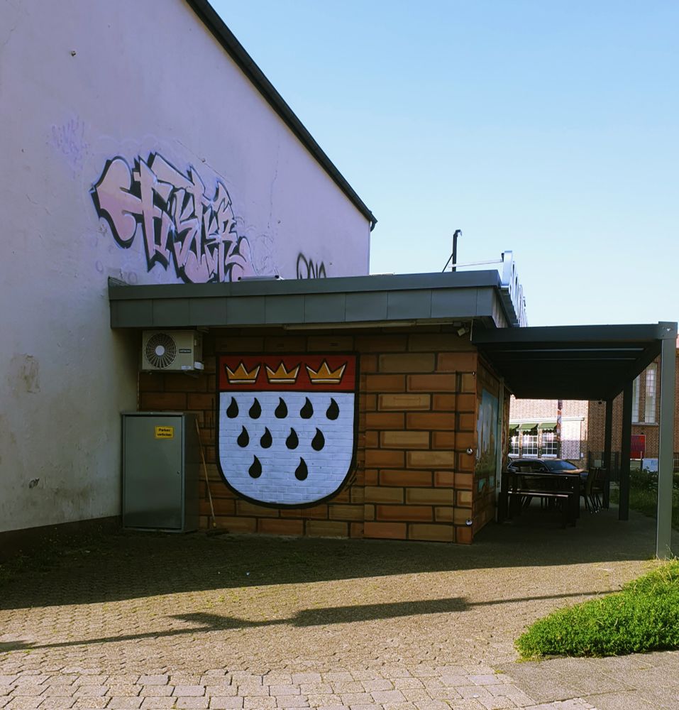 Kiosk mit einem aufgemalten Köln-Wappen auf der seitlichen Ziegelwand.